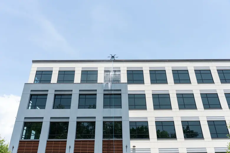 Drone soft washing a building exterior